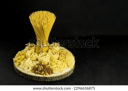 A variety of pasta and spaghetti on a dark background. Raw pasta for cooking Italian cuisine on a wooden table on a dark background. copy space