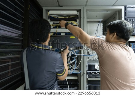 The engineer in a data processing center of ISP Internet Service Provider hold fiber patch cords Royalty-Free Stock Photo #2296656013