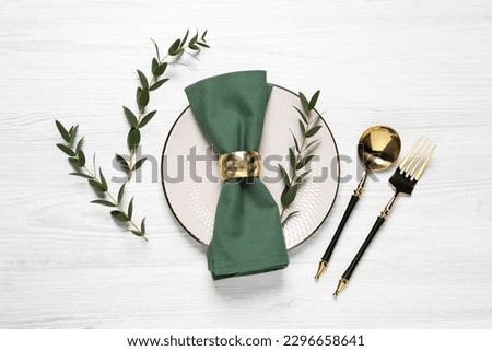 Stylish setting with cutlery and eucalyptus leaves on white wooden table, flat lay Royalty-Free Stock Photo #2296658641
