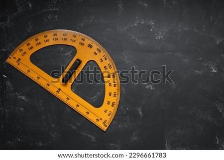 Protractor with measuring length and degree markings on blackboard, top view. Space for text