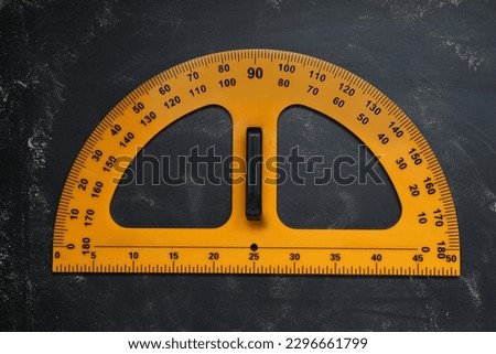 Protractor with measuring length and degree markings on blackboard, top view