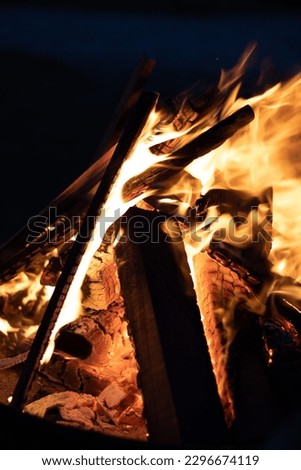 a picture taken at night neer a fireplace. blocks of wood fireing away. picture taken upclose.