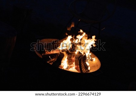 a picture taken at night neer a fireplace. blocks of wood fireing away. picture taken upclose.