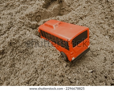 red plastic car toy on the sand