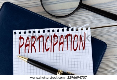 The word PARTICIPATION on a white sheet of paper against the background of a fragment of a notebook and a pen. Info concept Royalty-Free Stock Photo #2296694757
