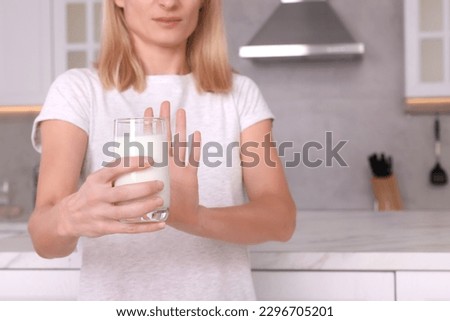 Woman with glass of milk suffering from lactose intolerance in kitchen, closeup. Space for text Royalty-Free Stock Photo #2296705201