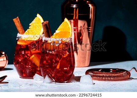 Negroni mezcalito cocktail drink with mexican mezcal, vermouth, bitter, herbal liqueur, orange, cinnamon and ice. Dark green background, hard light and shadow pattern Royalty-Free Stock Photo #2296724415