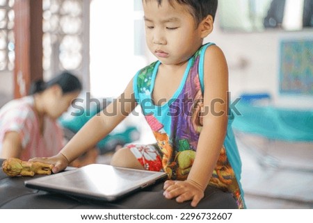 Adorable little boy playing tablet computer watching cartoon in house