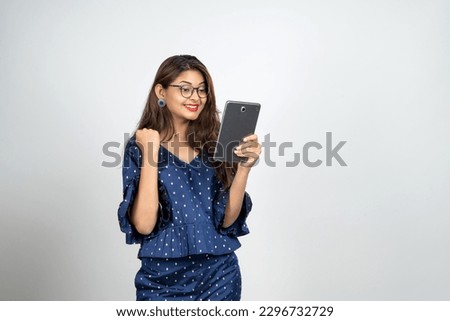 Image of young woman, company worker in glasses, smiling and holding digital tablet, standing over white background