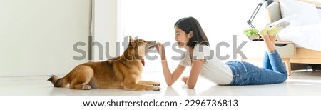 Banner cover design. Jocund young Asian woman lying on floor playing with Shiba Inu, Japanese dog. Cheerful and nice couple with people and pet. Pet Lover concept