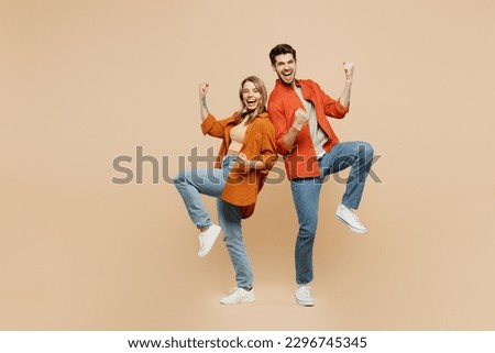 Full body young couple two friends family man woman wear casual clothes together doing winner gesture celebrate clenching fists say yes isolated on pastel plain beige color background studio portrait