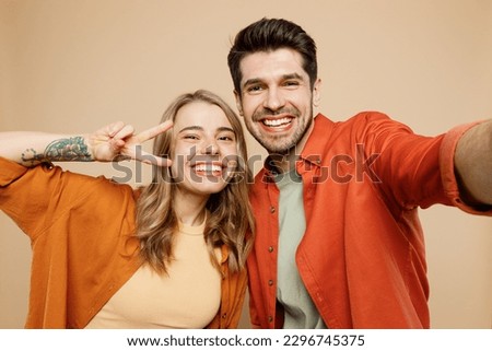 Close up young couple two friends family man woman wear casual clothes looking camera doing selfie shot pov on mobile cell phone together isolated on pastel plain light beige color background studio