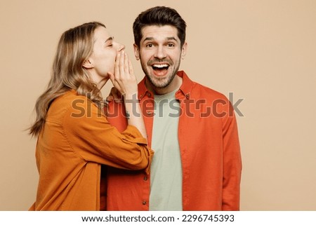 Young couple two friends family man woman wear casual clothes whisper gossip and tell secret behind her hand sharing news together isolated on pastel plain light beige color background studio portrait Royalty-Free Stock Photo #2296745393