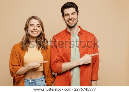 Young cheerful happy fun couple two friends family man woman wear casual clothes point index finger aside on area mock up together isolated on pastel plain light beige color background studio portrait Royalty-Free Stock Photo #2296745397