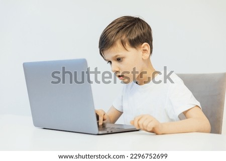 boy stares intently at laptop sitting at a desk in a classroom education online school