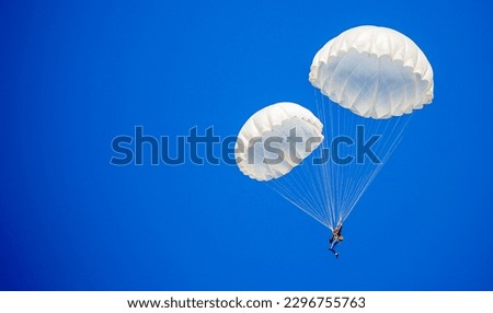 Skydiving. Flying parachutists against the background of the blue sky and mountains. Extreme sport and entertainment. Royalty-Free Stock Photo #2296755763