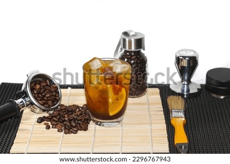 Americano Ice Coffee and coffee beans spread around the bamboo bar mat in the concept isolate picture.