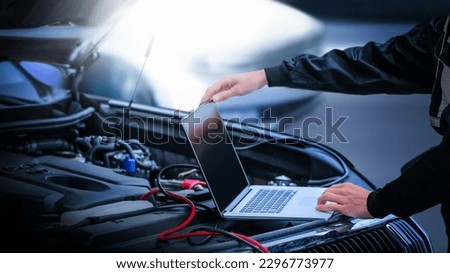Car diagnostic service close up  computer and modern mechanic in garage. Auto mechanic using computer software for diagnostics engine working and repairing car in a garage. Royalty-Free Stock Photo #2296773977