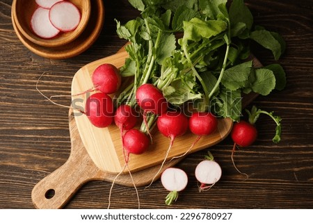Fresh red radish and kitchen board on wooden background. Flat lay. Royalty-Free Stock Photo #2296780927
