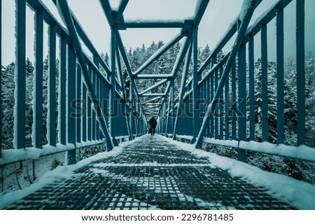 silhouette of man on the metal bridge in winter mountains