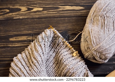 Knitted sweater with a knitting needles. Close up photo on grey background with copy space. Knitting class concept. home hobbies Royalty-Free Stock Photo #2296783223
