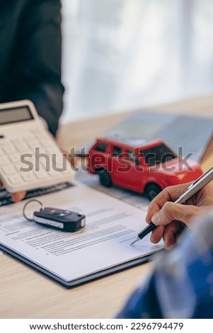 The car dealership or sales manager offers to sell the car and explain the terms of signing the car and insurance contract with the key fob.  Portrait Picture