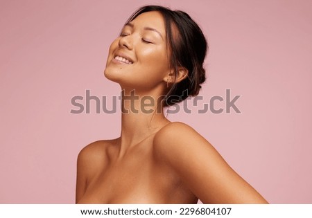 Pretty woman with beautiful and glowing skin. Female model with eyes closed and smiling against pink background. Royalty-Free Stock Photo #2296804107