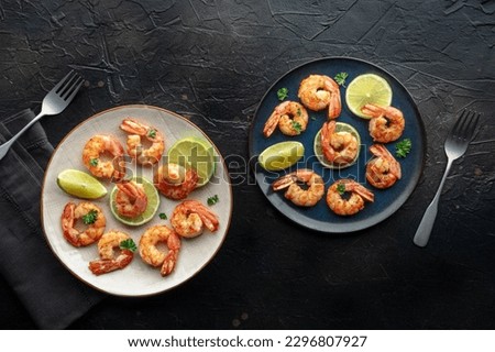 Shrimps, overhead flat lay shot. Fried shrimp with lime, two plates, shot from the top on a black slate background Royalty-Free Stock Photo #2296807927