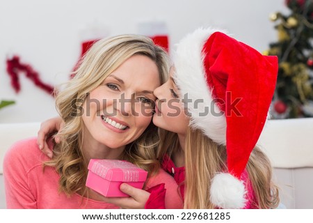 Festive mother and daughter with gift at home in the living room