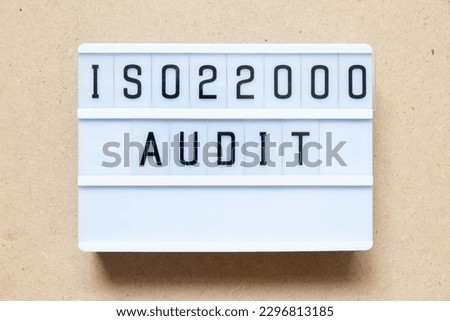 Lightbox with word ISO 22000 audit on wood background