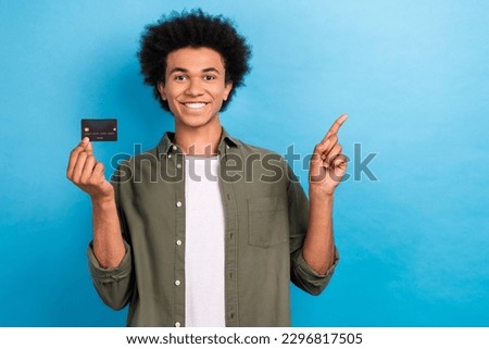 Photo of positive handsome man arm hold debit card indicate finger empty space isolated on blue color background