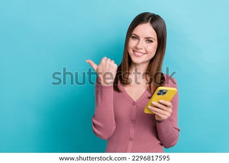 Photo of young smart phone user girl new gadget recommend pointing finger empty space create own design app isolated on cyan color background