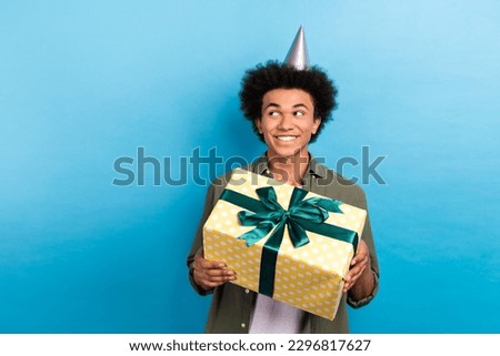 Portrait of funky man with perming coiffure wear khaki shirt holding gift box look empty space shopping isolated on blue color background