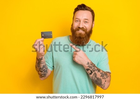 Portrait of attractive positive man wear stylish green clothes hold plastic card nfc payment shopping isolated on yellow color background