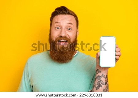 Photo of young funny excited beard red hair guy demonstrate smartphone display online food delivery service promo isolated on yellow color background