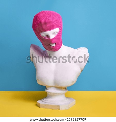 Antique statue bust wearing pink balaclava against blue background. Modern trends, swag style, youth culture. Concept of creativity, modernity and vintage, antique art. Inspiration and imagination
