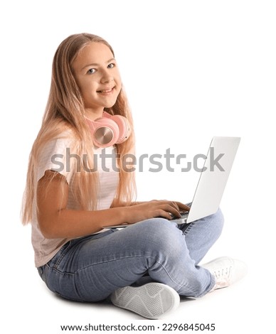 Little girl with headphones using laptop on white background