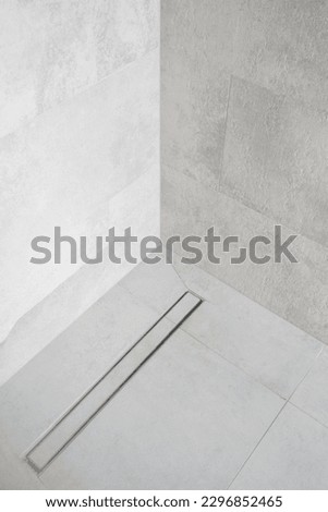 linear shower drain on tiled floor of modern enclosure in luxury bathroom, water disposal system, detail in loft washroom interior, minimalistic style Royalty-Free Stock Photo #2296852465