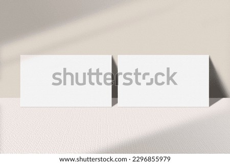 Realistic business card mockup leaning on the table. Simple two blank business cards on an elegant light background. Two sides of the business card mock up with shadow overlay effect