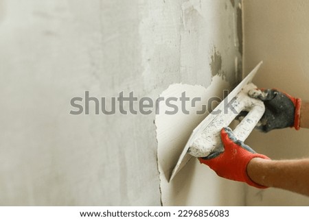 Worker plastering walls with gypsum plaster and spatula . Construction of house and home renovation concept. Close up of stucco and handyman hands with trowel Royalty-Free Stock Photo #2296856083