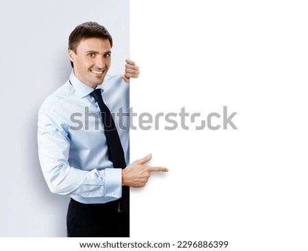 Image of business man, employee, professional in confident shirt wear. Businessman stand behind, hang over, show point finger empty white banner signboard. Isolated grey gray background