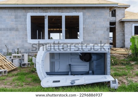Vacant portable toilet fallen in front of a single-family house under construction in a suburban development in southwest Florida, for motifs of wind or accident, deterioration, mischief Royalty-Free Stock Photo #2296886937