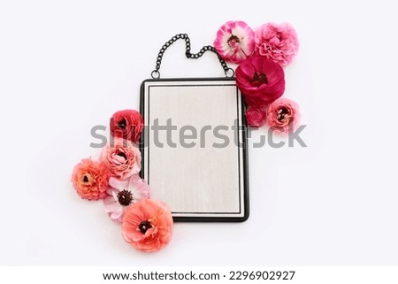 top view of pink flowers and black elegant empty frame over white background. For mock up, copy space