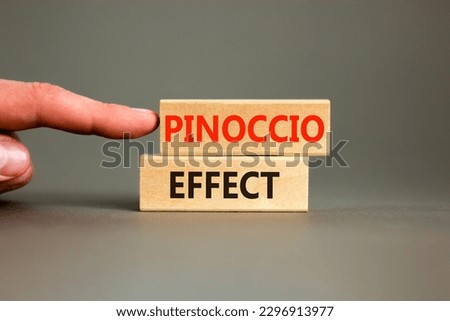 Pinoccio effect symbol. Concept words Pinoccio effect on wooden blocks on a beautiful grey background. Businessman hand. Business and Pinoccio effect concept, copy space.