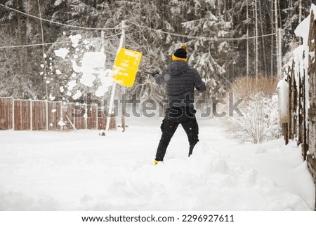 Deep drifts of snow after a heavy storm - an adult man clears the paths from snow with a shovel - digging a car out of a snowdrift Royalty-Free Stock Photo #2296927611