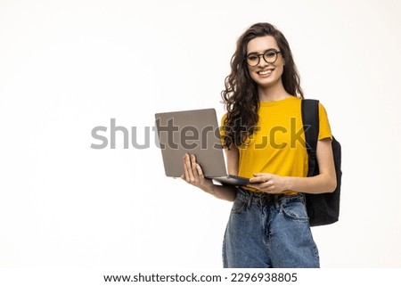 Happy cute student girl with backpack standing and holding laptop isolated on a white background