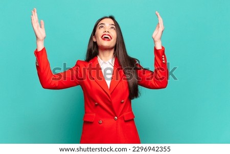 young pretty woman feeling happy, amazed, lucky and surprised, celebrating victory with both hands up in the air. business concept