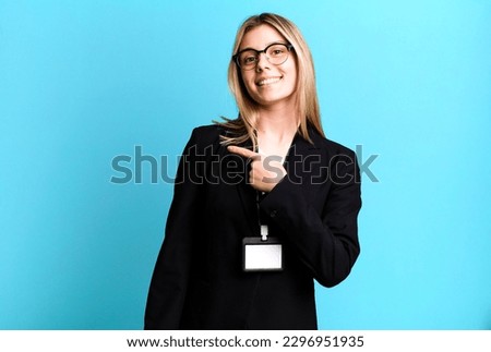 young pretty woman looking excited and surprised pointing to the side. id card accreditation concept