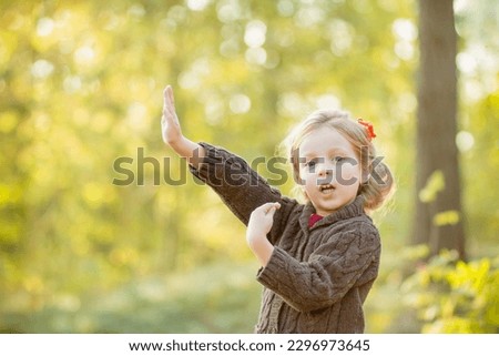 happy little child, girl 4-5 year old playing outdoor. Girl is wearing warm jacket. she is dancing, jumping,spending a weekend in autumn park. Autumnal mood.Childhood. Autumn season.