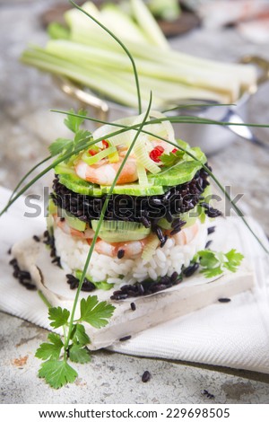 Presentation of a second tower gourmet dish of white rice and black with shrimp and zucchini